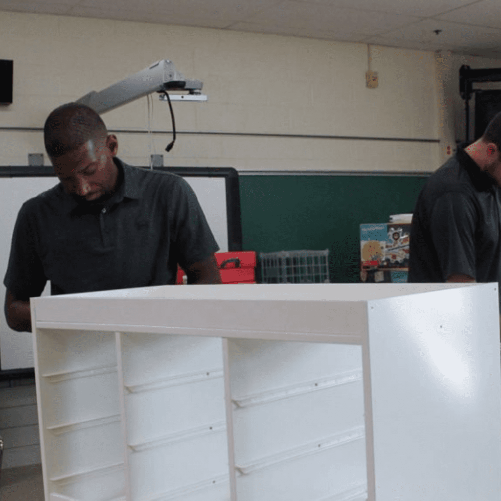 two men are working on a white cabinet