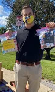 a man wearing a face mask and holding up some mail