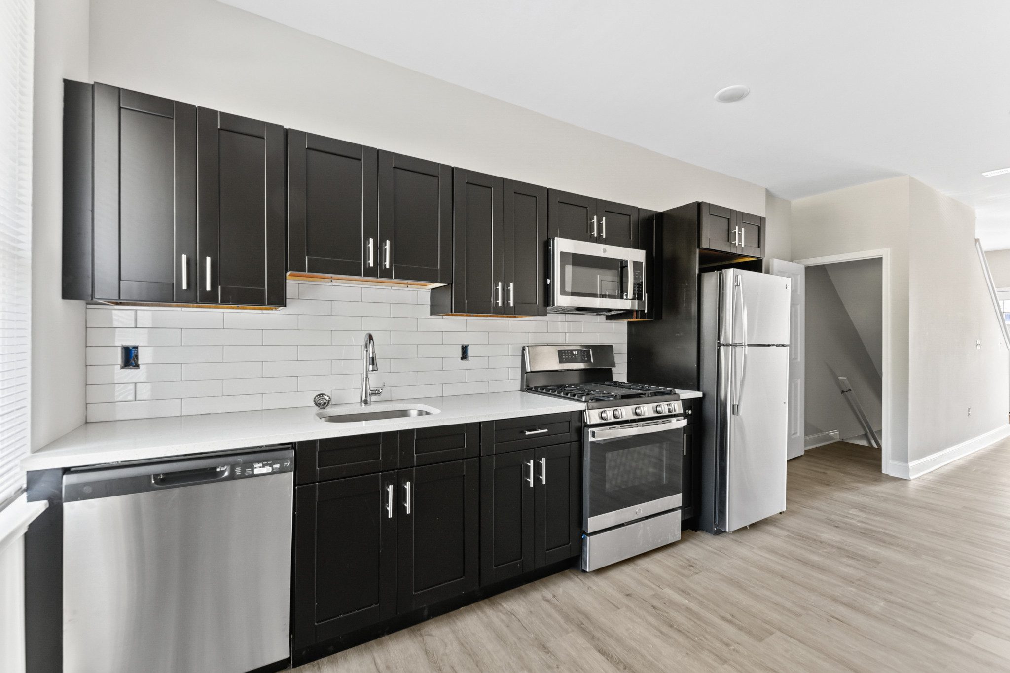 a kitchen with black and white cabinets and stainless steel appliances