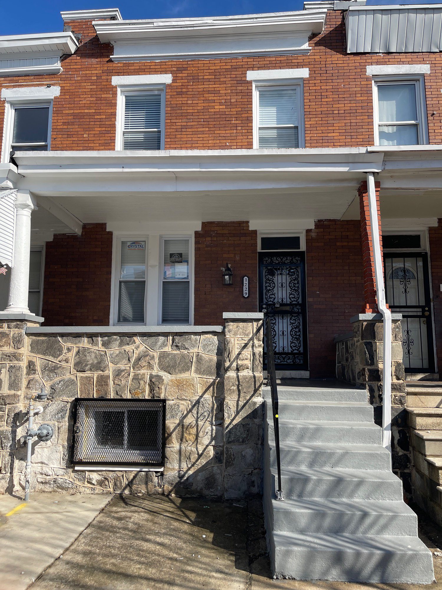 a two story brick house with stairs leading up to the front door